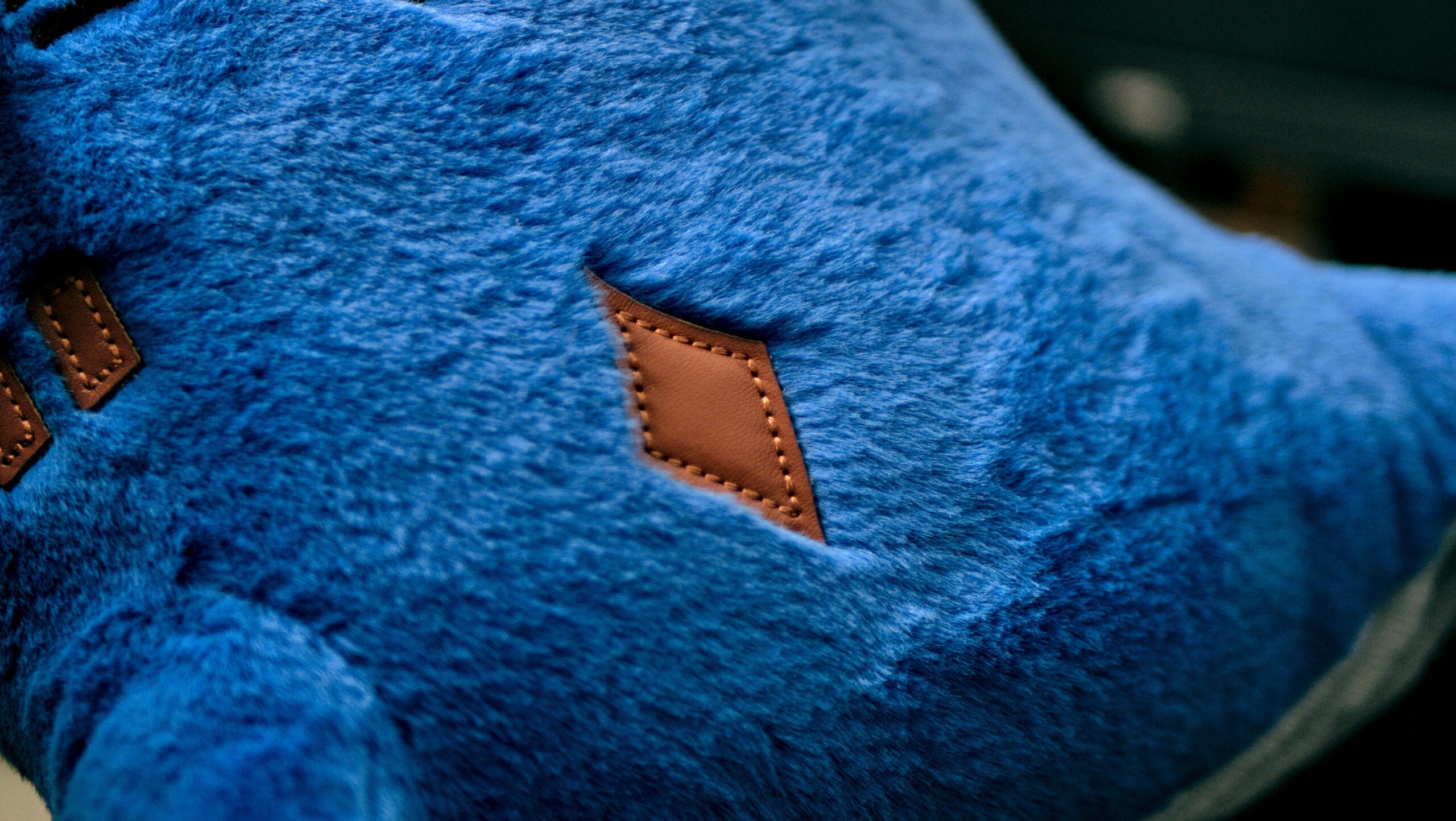 Close-up of Marlow designer toy showing premium faux rabbit fur, hand-stitched PU leather patch, and high-quality embroidery details.